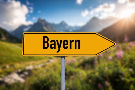 Gelbes Ortsschild von Bayern vor Bergkulisse