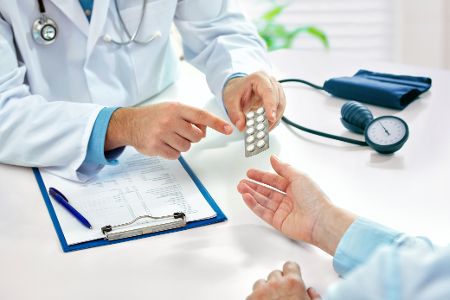 Arzt erklärt Patient die Wirkung von Tabletten in einem Blister