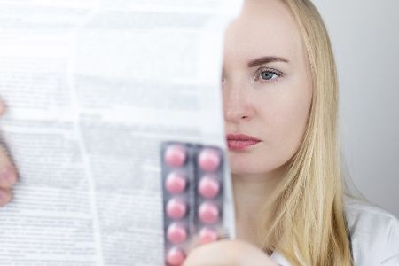 Frau mit einem Blister in der Hand liest die Packungsbeilage