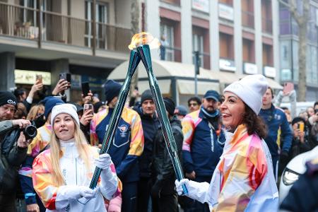 Olympische Winterspiele: Athletinnen beim Fackellauf mit der Flamme in Cortina D'ampezzo.