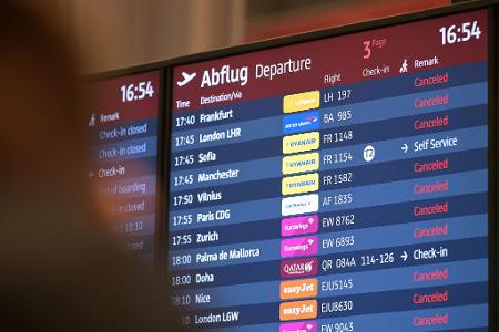 Passagiere blicken auf eine Anzeigetafel am Hauptstadtflughafen BER.