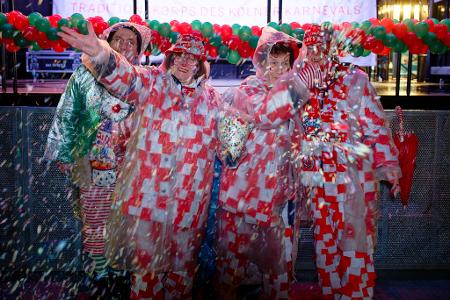 Erste Jecken warten im Regen auf dem Alter Markt an Weiberfastnacht auf den Beginn des Straßenkarnevals in Köln.