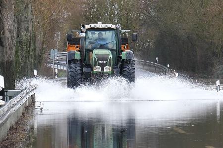 Ein Traktor fährt über die überschwemmte Lahnparkstraße in Heuchelheim.