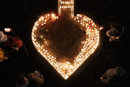 Passanten entzünden auf dem Neumarkt Kerzen am 81. Jahrestag der Zerstörung Dresdens.