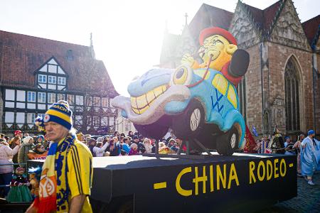 Karnevalisten nehmen mit einem Motivwagen zum Thema Volkswagen am Karnevalsumzug 