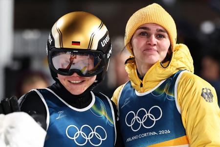 Agnes Reisch (l, Deutschland) reagiert nach ihrem Sprung von der Großschanze neben Teamkollegin Selina Freitag (Deutschland) bei den Olympischen Winterspielen Mailand Cortina 2026.