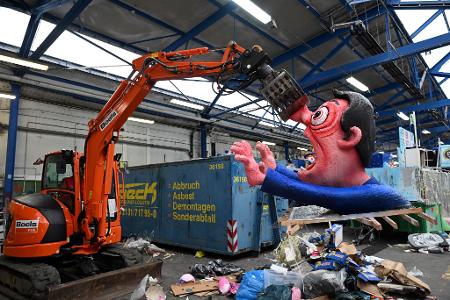 Ein Bagger hebt in Düsseldorf eine Pappfigur eines Rosenmontagszugs in den Müll. Nachdem die Motive zahlreiche Zuschauer begeisterten, werden sie abgerissen.