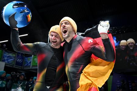 Johannes Lochner (Pilot, l) und Georg Fleischhauer bejubeln ihren ersten Platz im Zweierbob bei den Olympischen Winterspielen Mailand Cortina 2026.