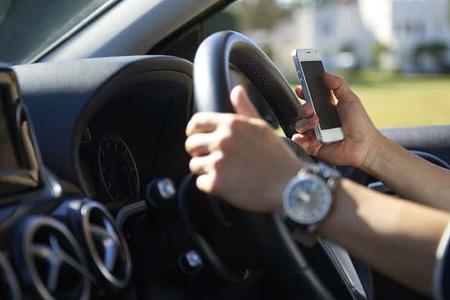 Young woman texting while driving