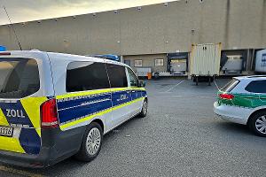 Streifenwagen des Zolls vor einer Lagerhalle