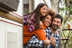 Mom dad and daughter mixed-race family driving van home on wheels camper together. Adventure on caravanning. Road trip voyage with children kids