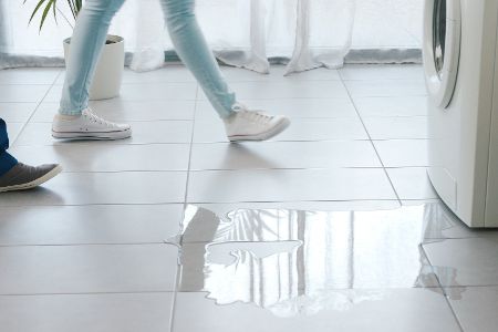 Zwei Personen vor einer ausgelaufenen Waschmaschine