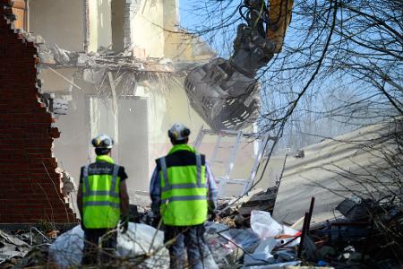 Arbeiter beobachten die Abrissarbeiten eines Baggers am Haus Seeblick am Brodtener Steilufer an der Ostsee.