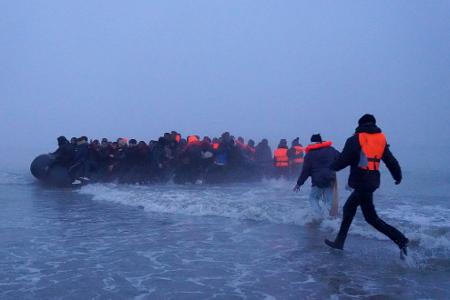 Menschen, bei denen es sich vermutlich um Migranten handelt, besteigen ein kleines Boot am Strand von Gravelines, Frankreich, um den Ärmelkanal zu überqueren.