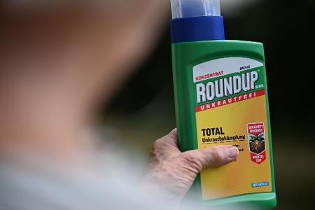 Eine Frau hält eine alte Packung des Unkrautvernichters Glyphosat in den Händen.