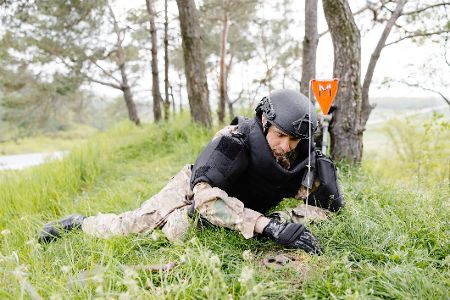 Mann in Schutzkleidung birgt eine Landmine