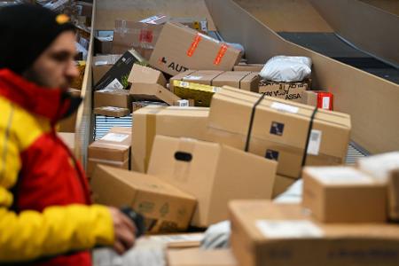 Ein DHL-Paketbote ist in einer Zustellbasis mit einer Vielzahl an Paketen beschäftigt. Der Logistikkonzern hat Jahreszahlen für 2025 vorgelegt, er hat profitablere Geschäfte gemacht als zuvor.