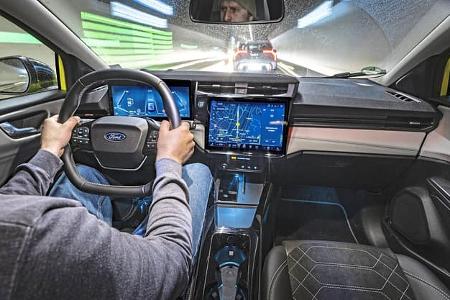 Innenraumaufnahme eines Ford Puma Gen-E Premium während der Fahrt durch einen Tunnel. Das Bild zeigt das Cockpit mit digitalem Kombiinstrument, großem Infotainment-Display und Fahrer am Steuer.