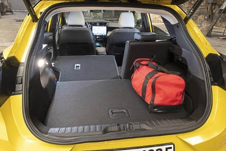 Kofferraum des Ford Puma Gen-E Premium mit umgeklappter Rückbank und roter Sporttasche, Blick nach vorn zum Cockpit.