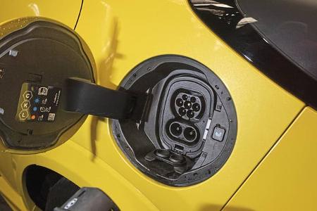 Detailaufnahme des Ladeanschlusses eines gelben Ford Puma Gen-E Premium während eines Ladevorgangs. Die Ladeklappe ist geöffnet, der CCS-Ladeanschluss ist sichtbar, und ein Ladekabel wird gerade angeschlossen.