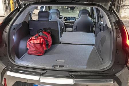 Kofferraumansicht des Kia EV3 58,3 kWh mit umgeklappter Rückbank und roter Tasche im Laderaum.