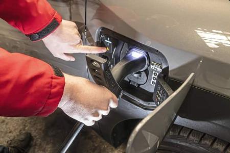 Ladeszene am Kia EV3 58,3 kWh: Eine Person steckt ein Ladekabel in die Ladebuchse eines Elektroautos.