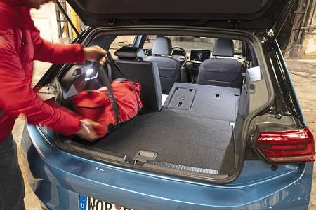 Kofferraumansicht eines VW ID.3 52 kWh mit umgeklappter Rückbank, eine Person lädt eine rote Tasche ein.