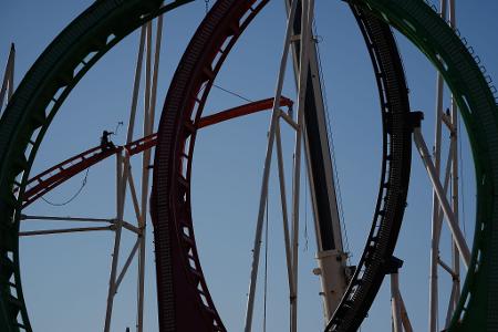 Eine Höhenkletterin nimmt in luftiger Höhe während der Aufbauarbeiten des Frühlingsdoms eine Schiene der Achterbahn auf dem Heiligengeistfeld in Hamburg entgegen.