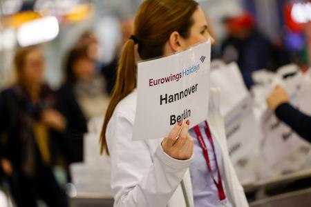 Eine Mitarbeiterin der Fluggesellschaft Eurowings hält ein Schild.