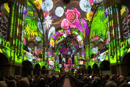 Menschen verfolgen in der Dresdner Martin-Luther-Kirche eine Lichtshow.