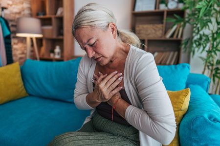 Ältere Frau packt sich voll Schmerzen an die Brust