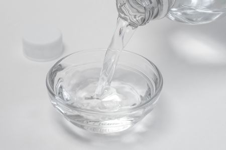 Aus einer Flasche wird eine durchsichtige Flüssigkeit in einer Glasschale gegossen