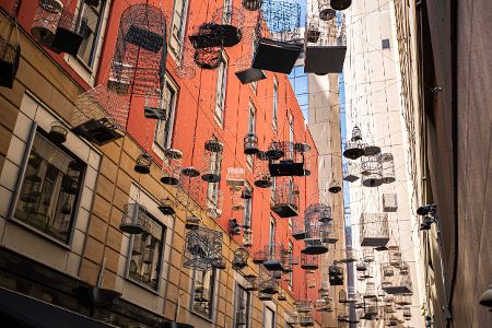 Leere Vogelkäfige hängen über einer Straße