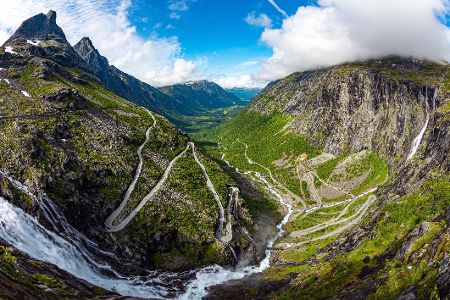 Serpentinenreiche Straße an einem Berg neben einem Wasserfall