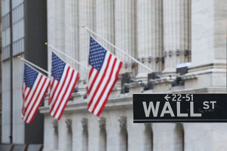 Straßenschild der Wall Street vor USA-Flaggen