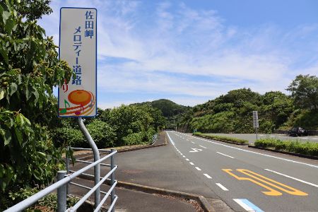 Straßenschild mit Noten drauf neben einer Straße