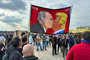 Demonstranten halten bei einer Kundgebung des Bündnisses "Eine Million Augenblicke für Demokratie" ein Banner, auf dem sich stilisiert US-Präsident Trump und Russlands Präsident Putin küssen.