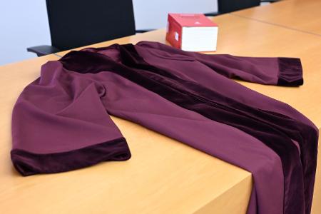 Die Robe zeichnet sich durch den tiefen Rot-Ton und den Samtbesatz an Ärmeln und Kragen aus. 