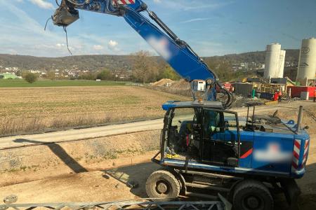 Der beschädigte Bagger steht an einer Baustelle neben den Bahngleisen.