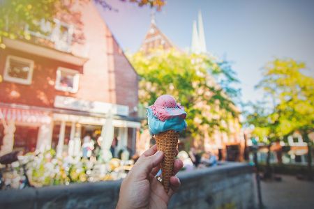 Hand hält Eis vor einer Straßenkulisse in Bremen