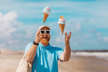 Mann jongliert mit zwei Eiswaffeln am Strand