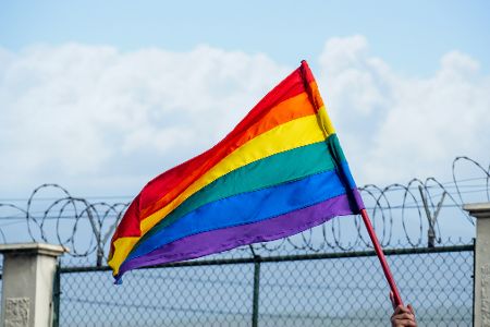 Pride-Flagge vor einem Gefängniszaun