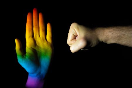 Geballte Faust neben einer regenbogenfarbenen Hand