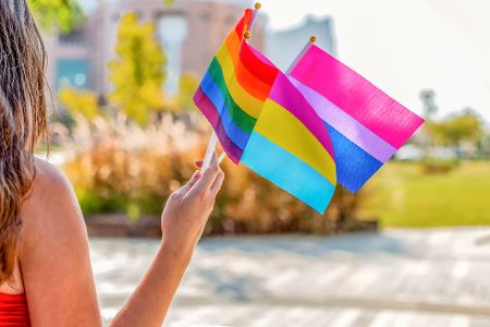 Frau hält verschiedene LGBTQIA-Fähnchen in der Hand