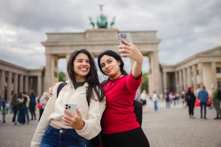 Zwei Frauen machen Arm in Arm ein Selfie vor dem Brandenburger Tor