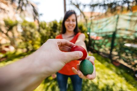 Zwei Menschen schlagen ihre Ostereier gegeneinander