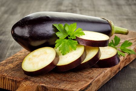 Halb aufgeschnittene Aubergine auf einem Holzbrett
