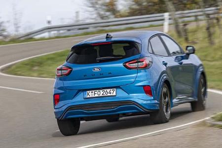 Ford Puma 1,0 EcoBoost in blauer Lackierung fährt auf einer kurvigen Landstraße. Das Fahrzeug ist aus der Heckperspektive zu sehen.