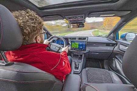 Innenaufnahme eines Ford Puma 1,0 EcoBoost während der Fahrt, Blick vom Fond auf Fahrer und Cockpit.