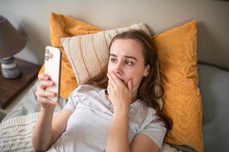 Frau mit entsetztem Gesicht starrt auf ihr Handy